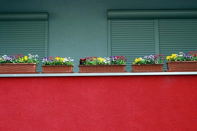 Balkón s červeným zábradlím a kvetináčmi s kvetmi.jpg